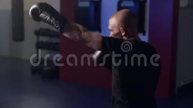 拳击手套中肌肉发达的拳击手，在健身房用影子击球，动作缓慢。微光场景
